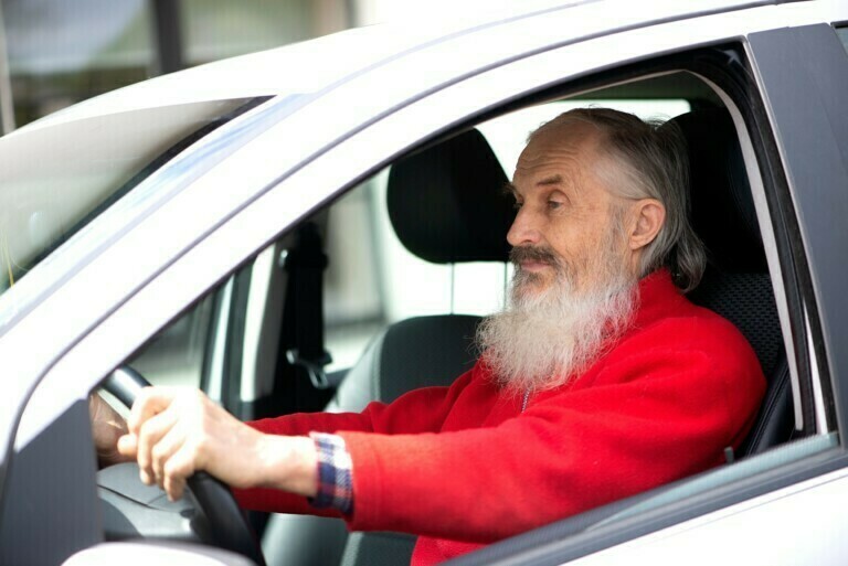 Retired elder senior man with long beard driving gray car